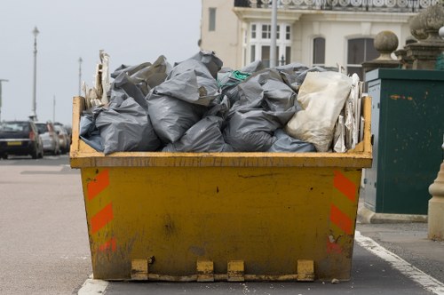 Crew placing a labelled skip in Maida Vale street showing recycling logos